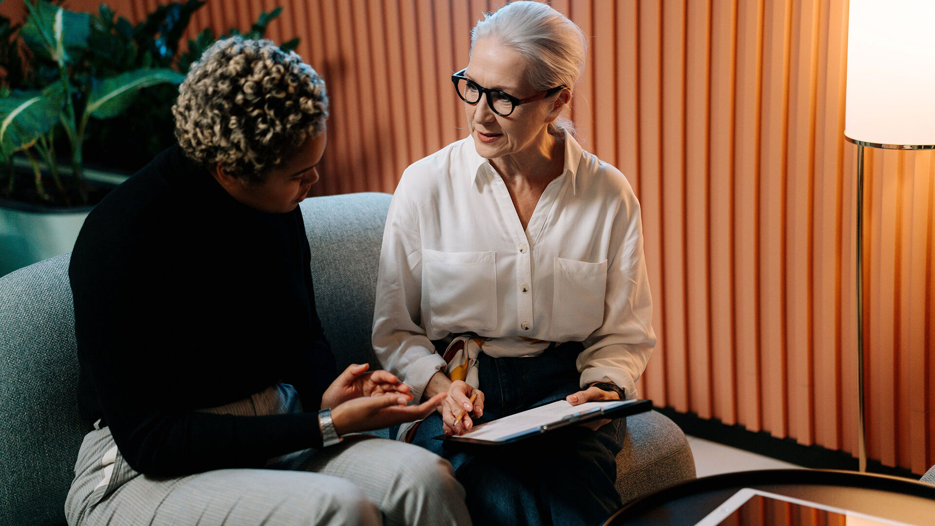 An older woman shakes the hand of a young woman in a job interview setting