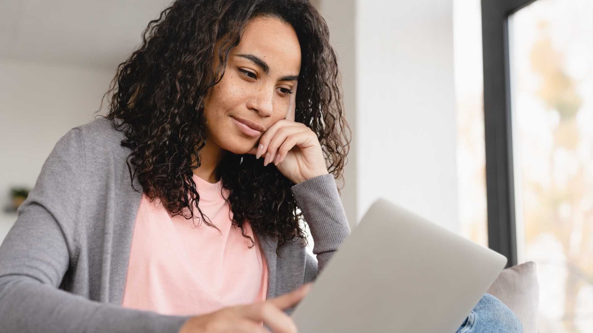 A woman is thoughtfully looking at a tablet