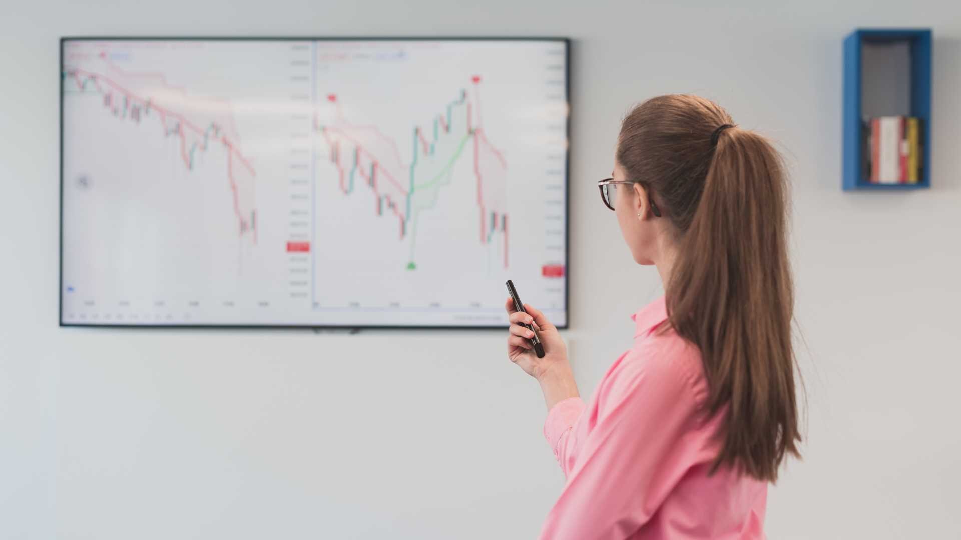 Woman with glasses and hair in a ponytail looking at board with learning metrics.