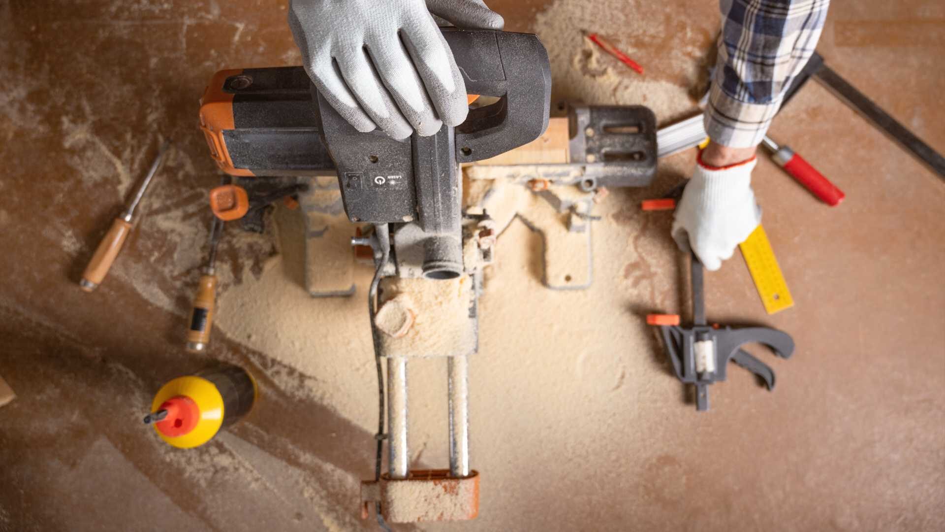 Construction worker cutting wood and using tools on a work station table.
