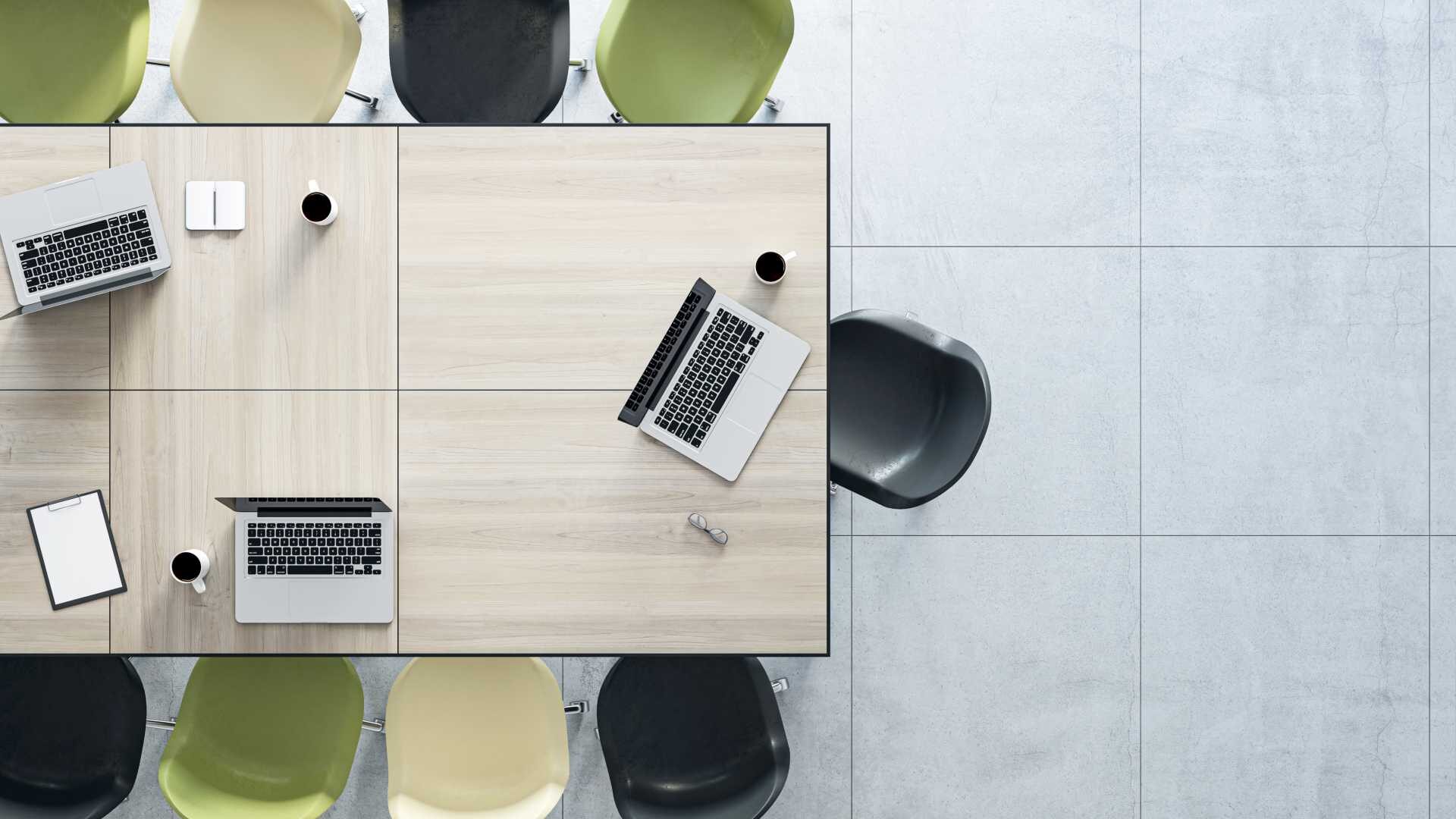 long table with alternating black and green chairs and three laptops and coffees on the table.