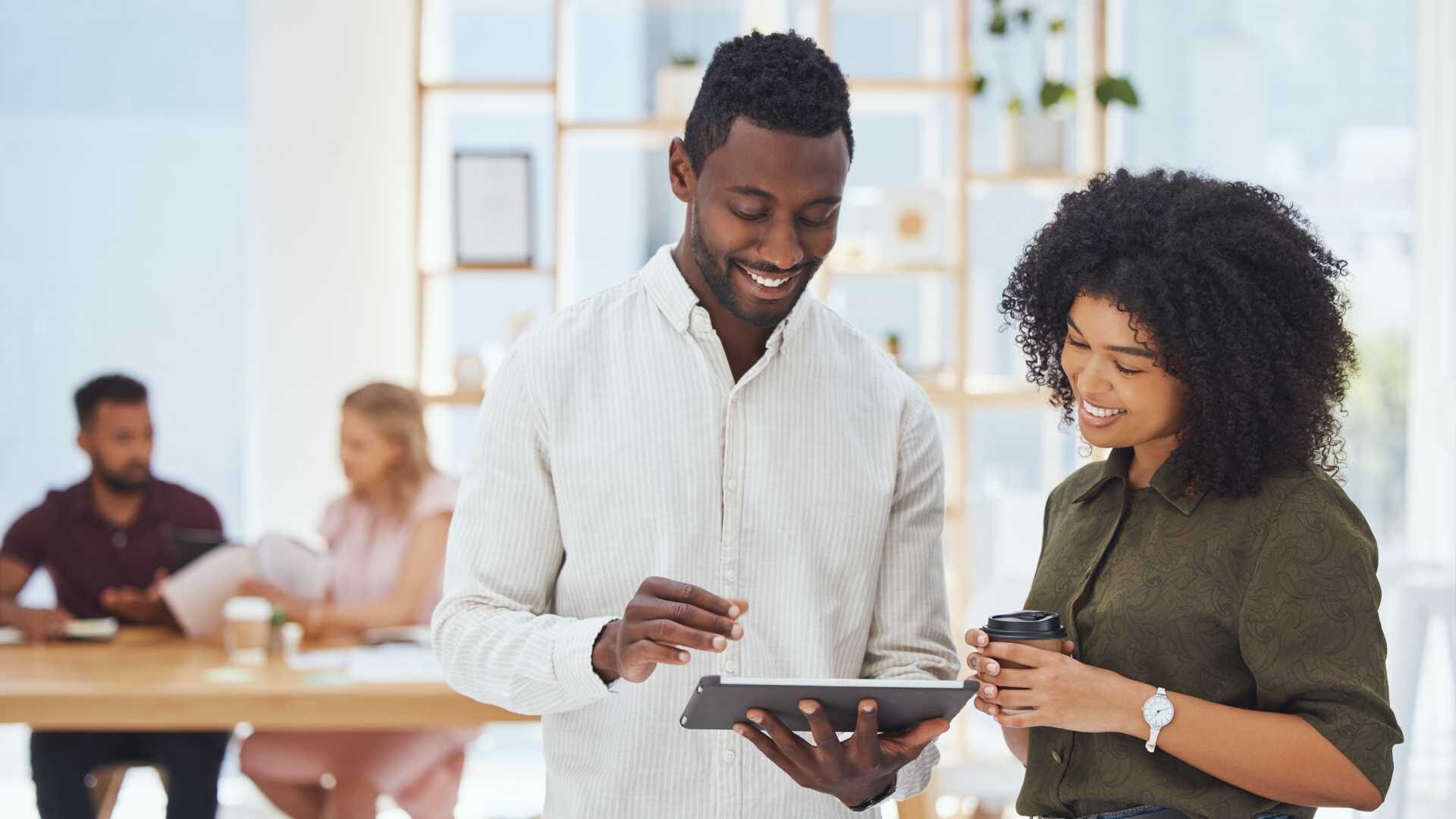 A male and female colleague engage in a conversation while looking at an iPad in a business setting
