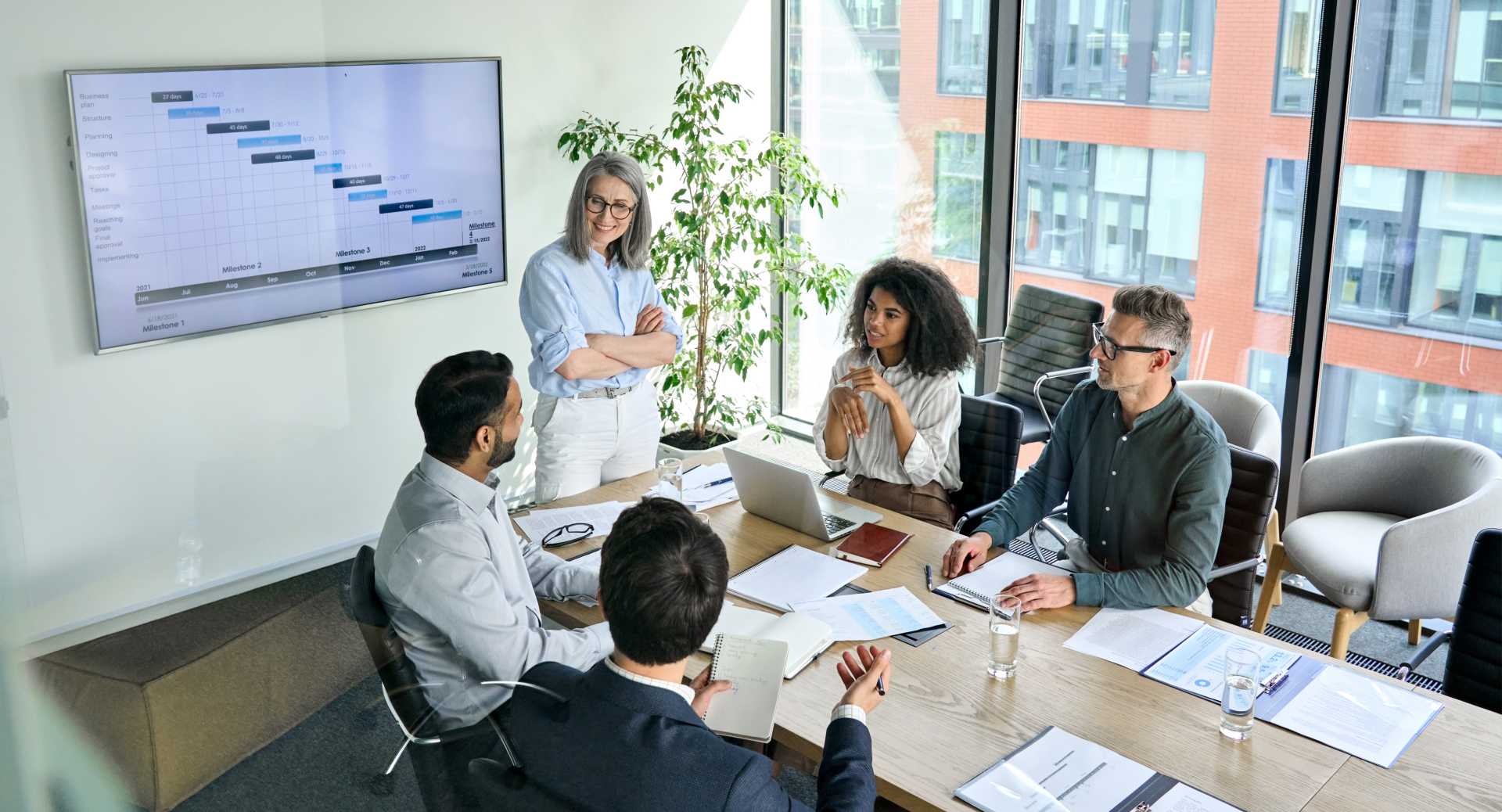 A businesswoman stands in front of a group of colleagues in a conference room