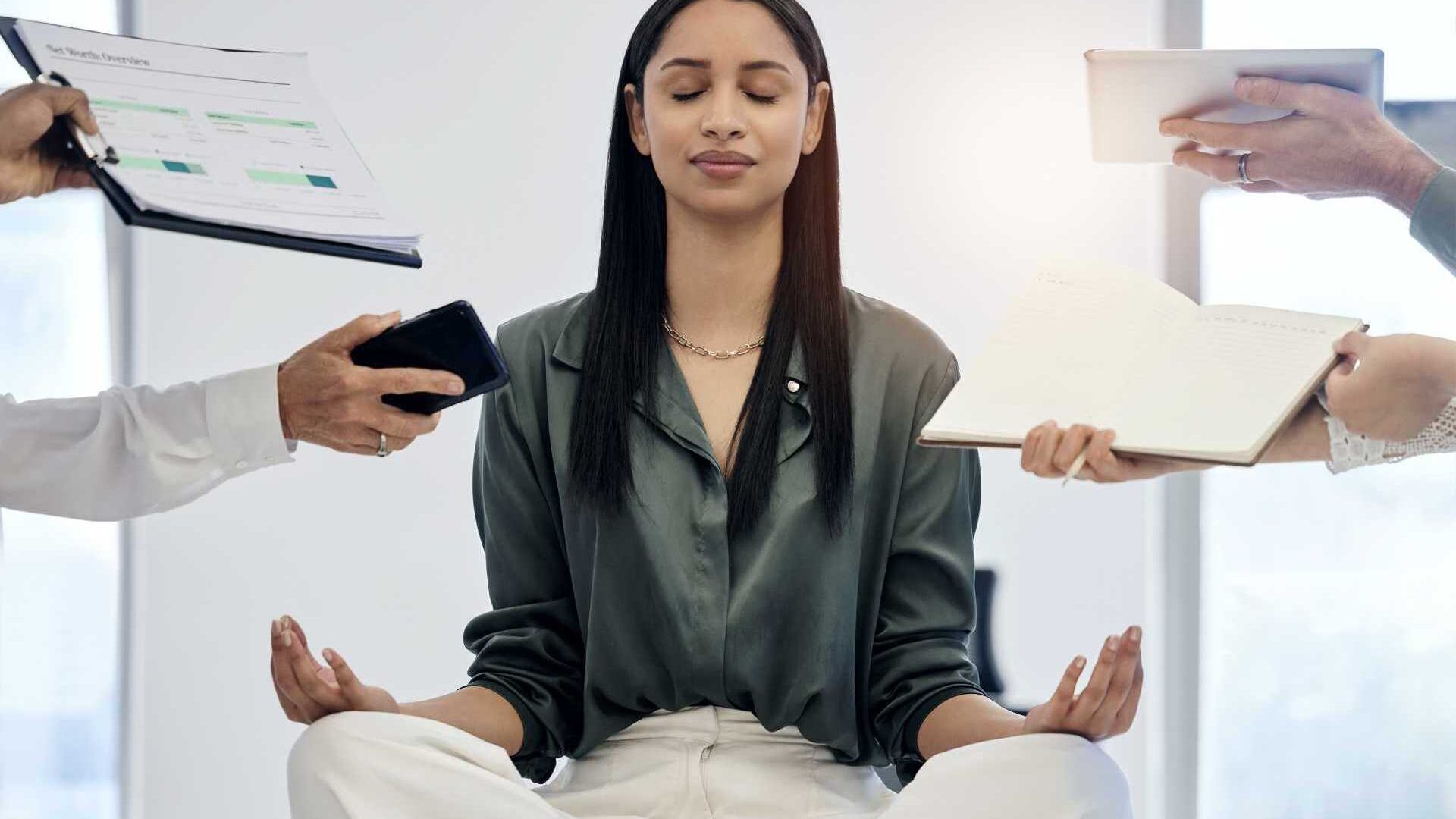 A professional woman sits in the lotus position meditating.