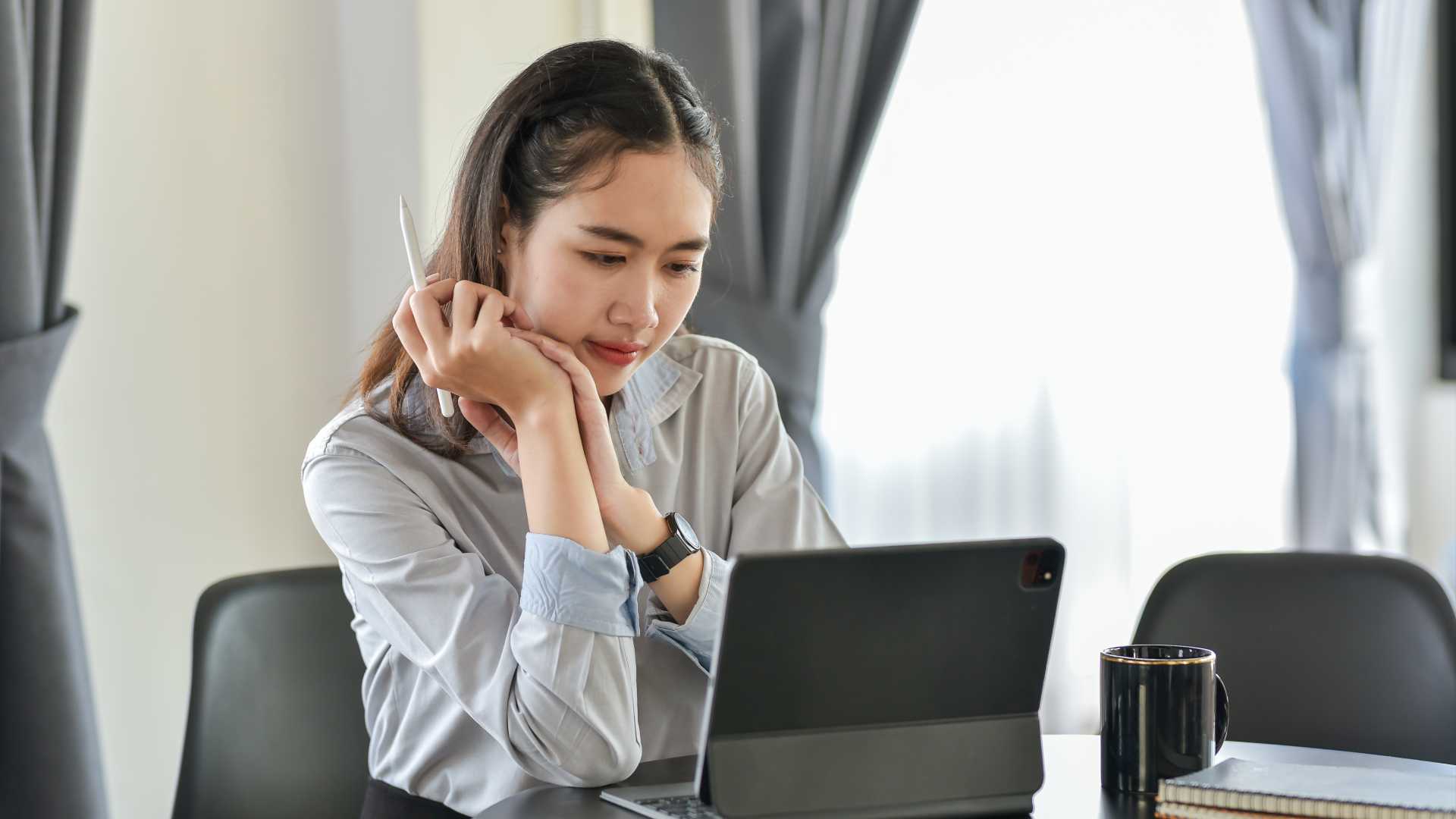 A young businesswoman reviews natural language processing models on her tablet.