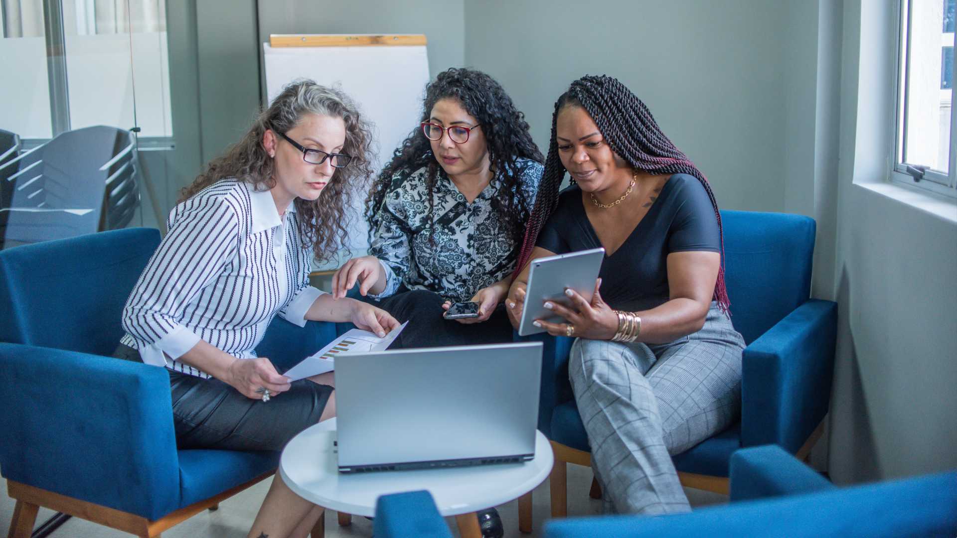 A group of coworkers are talking around a laptop