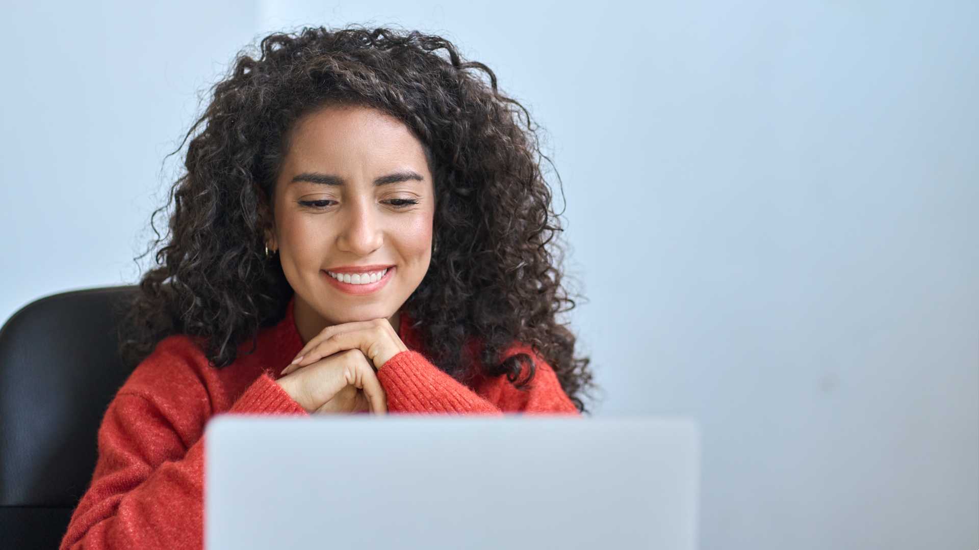 A person is smiling at a computer screen