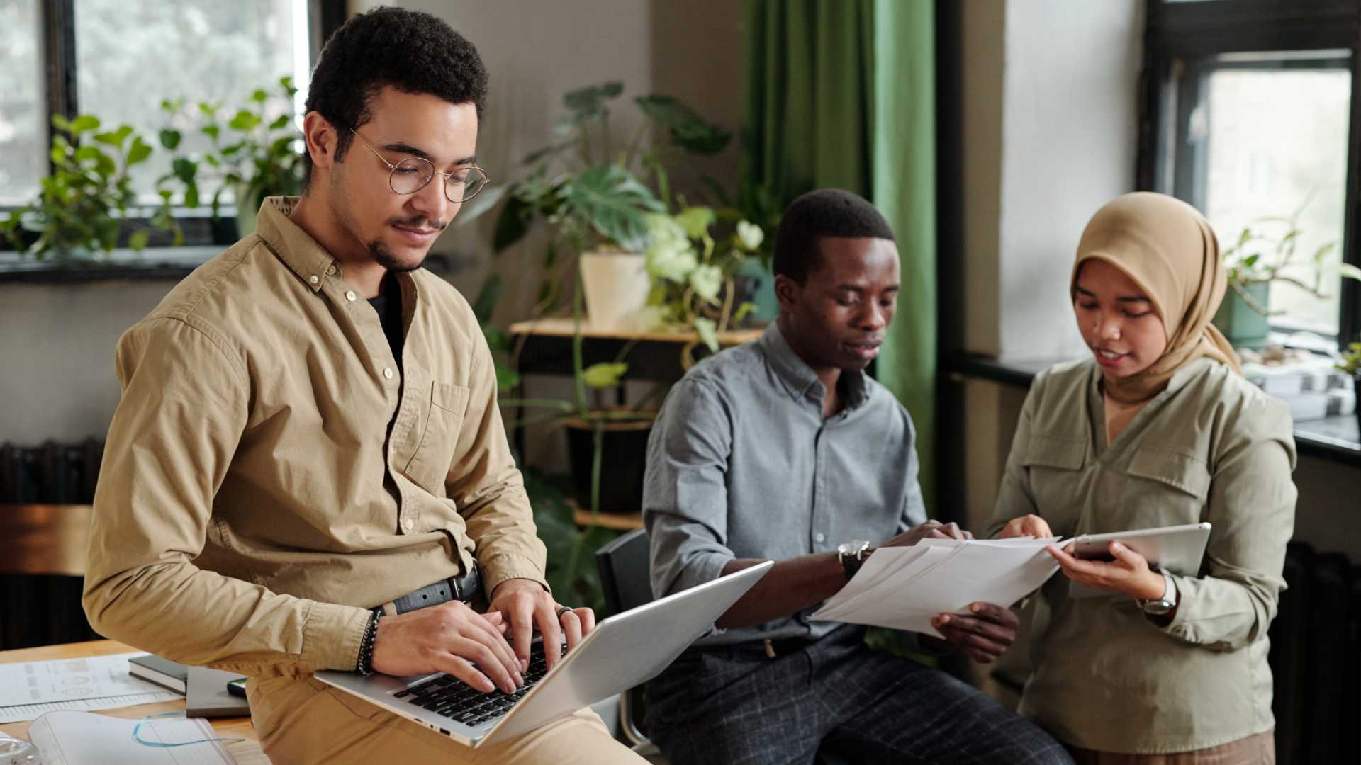A group of employees from diverse backgrounds collaborate in an open workspace