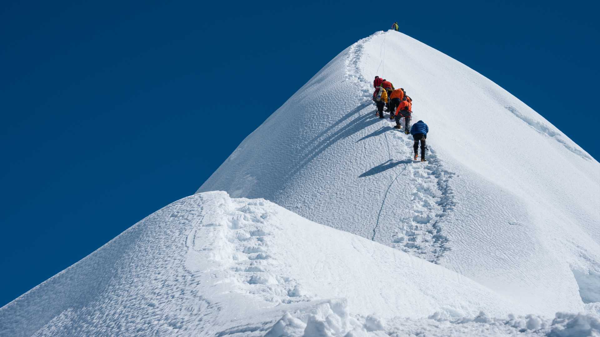 A group of hikers climb a snow-covered mountain