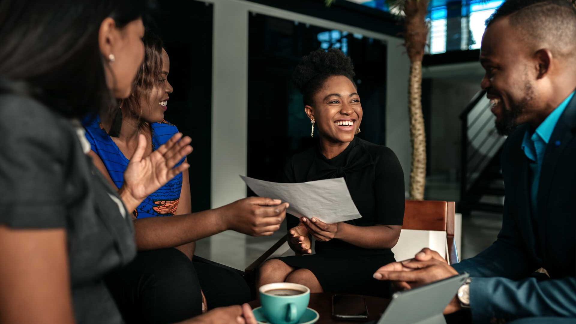 A group of colleagues collaborates over coffee in an open office space