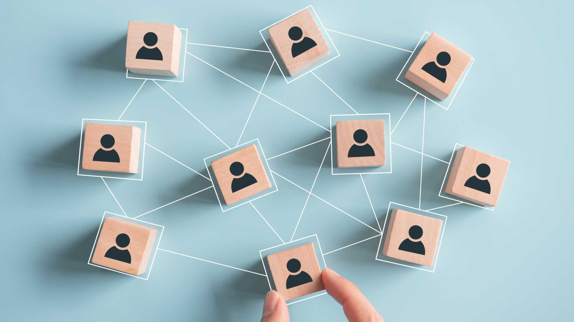 Fingers assembling blocks with human figures printed on, white connect the dots connecting the blocks