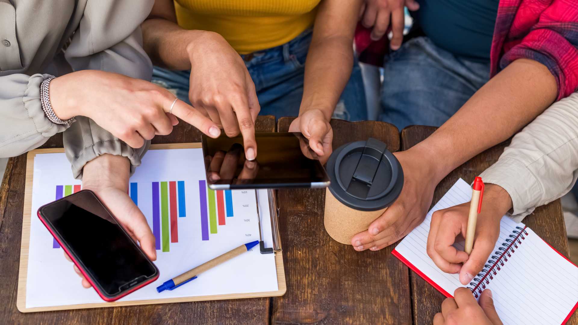 Close up Group Young Coworkers Together with cell phones, tablets, notebooks, and coffee on the desk