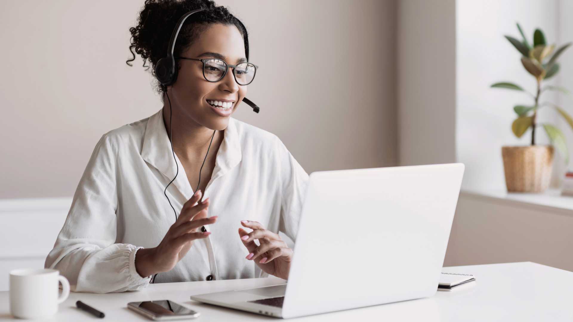 A business person wearing a headset is in a meeting on their laptop
