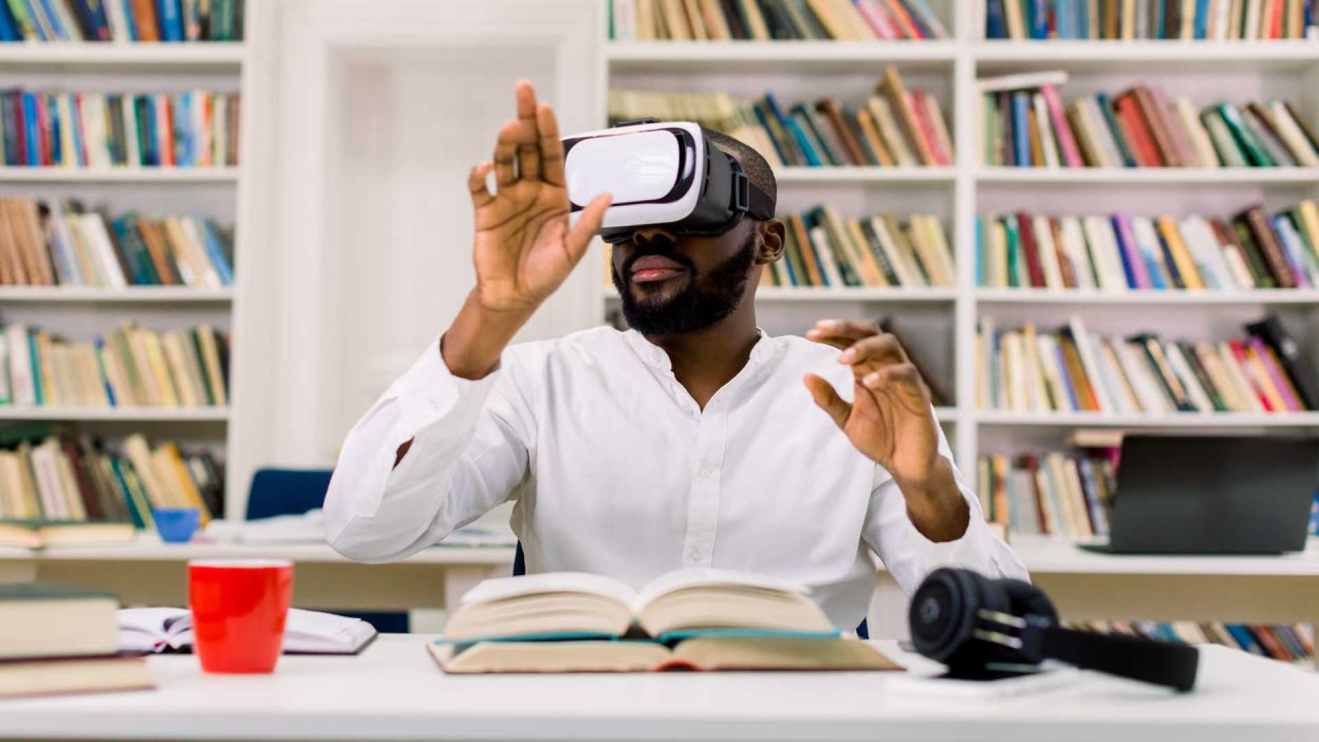 A man seated at a desk uses a virtual reality (VR) headset