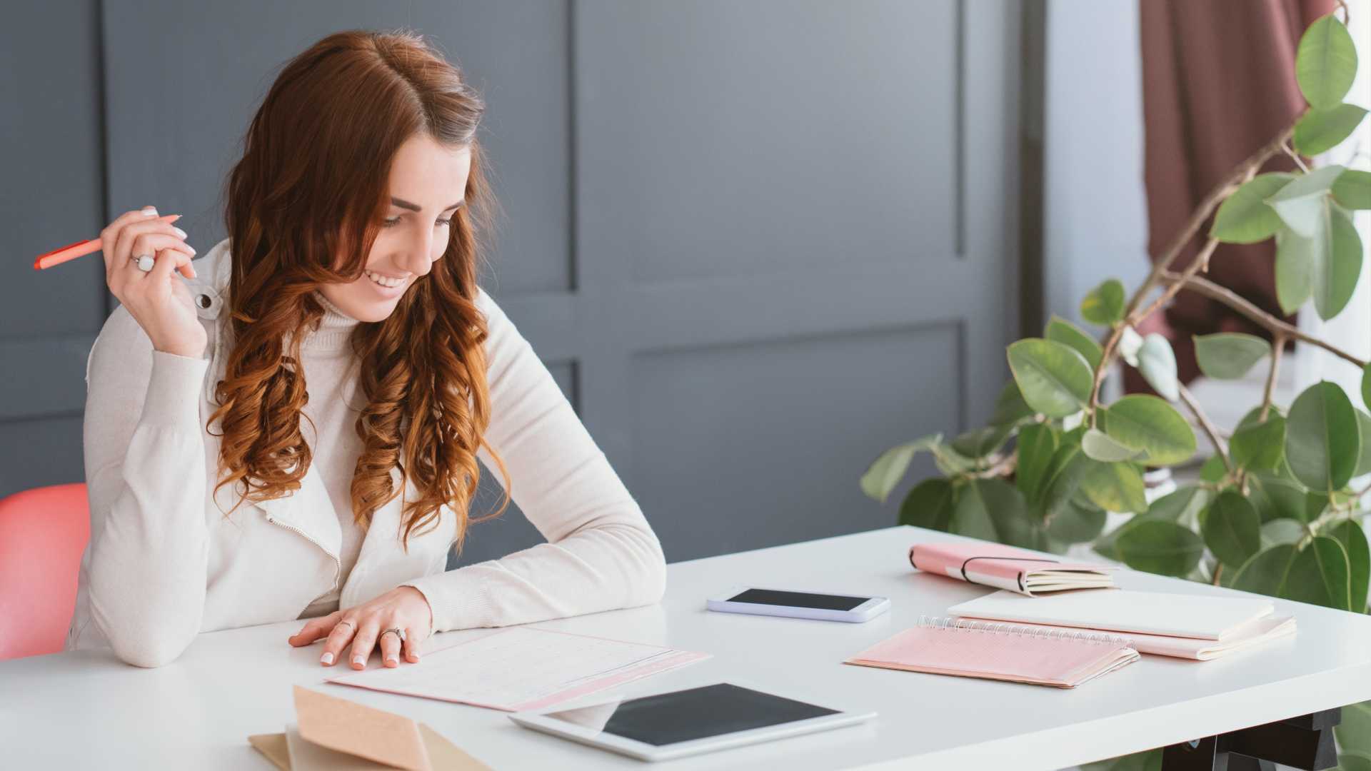 A woman working from home, planning her schedule with a pen in hand