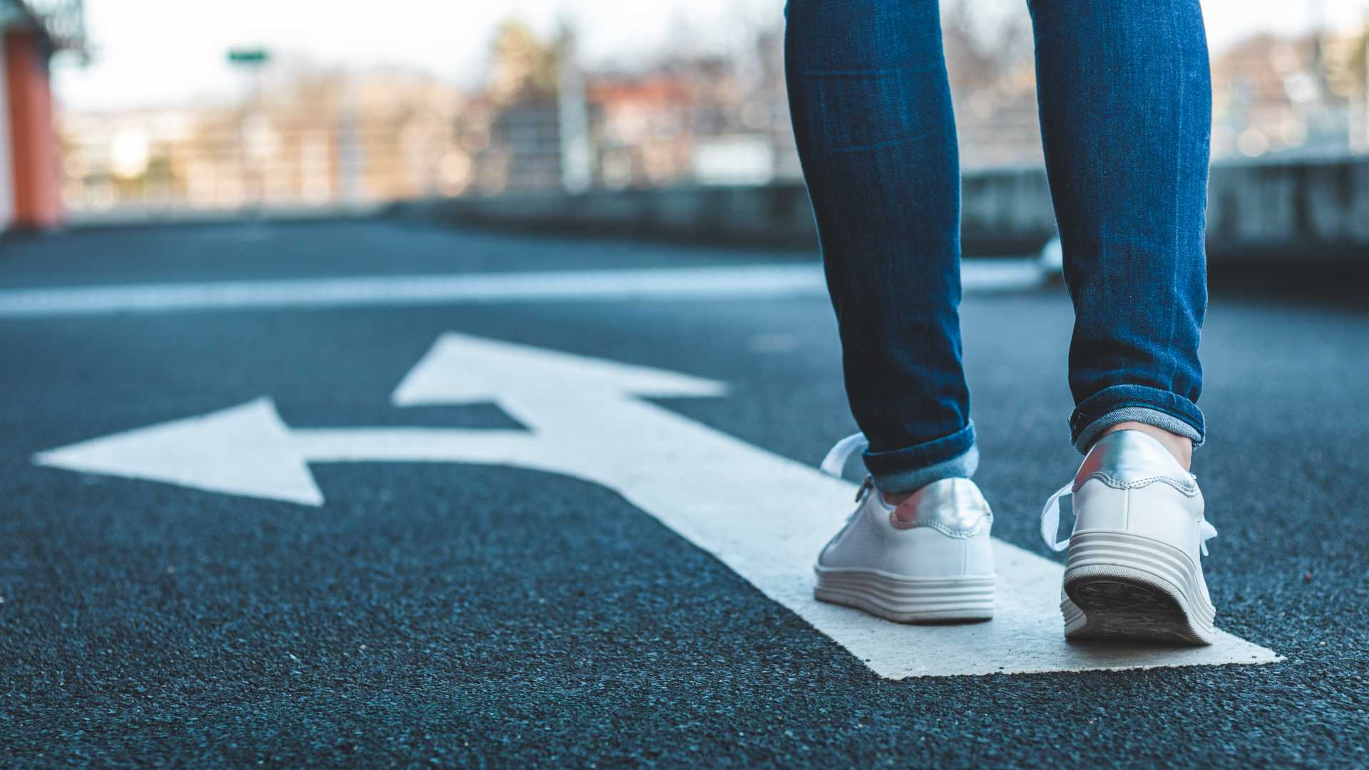 Person standing on a painted white street arrow,
