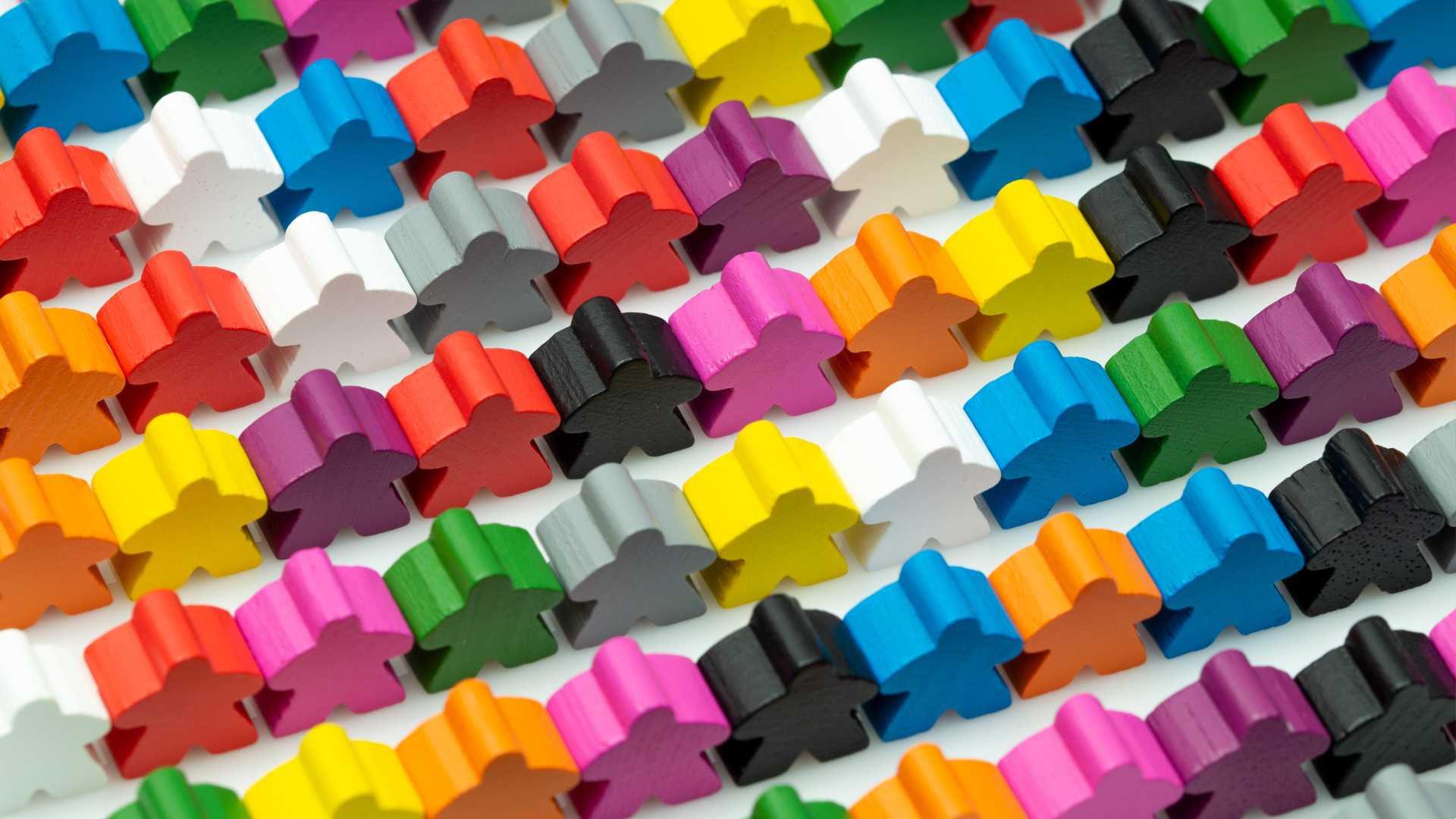 Wooden figurines of varying colors are lined up in rows
