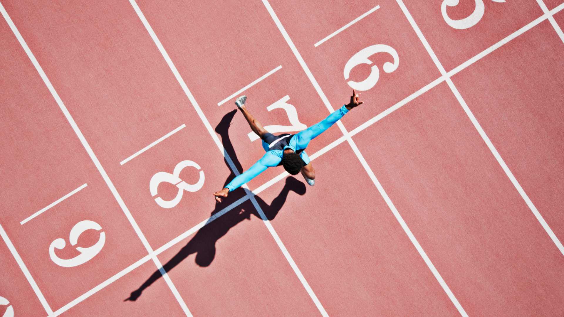A man crosses the finish line on a n outdoor running track