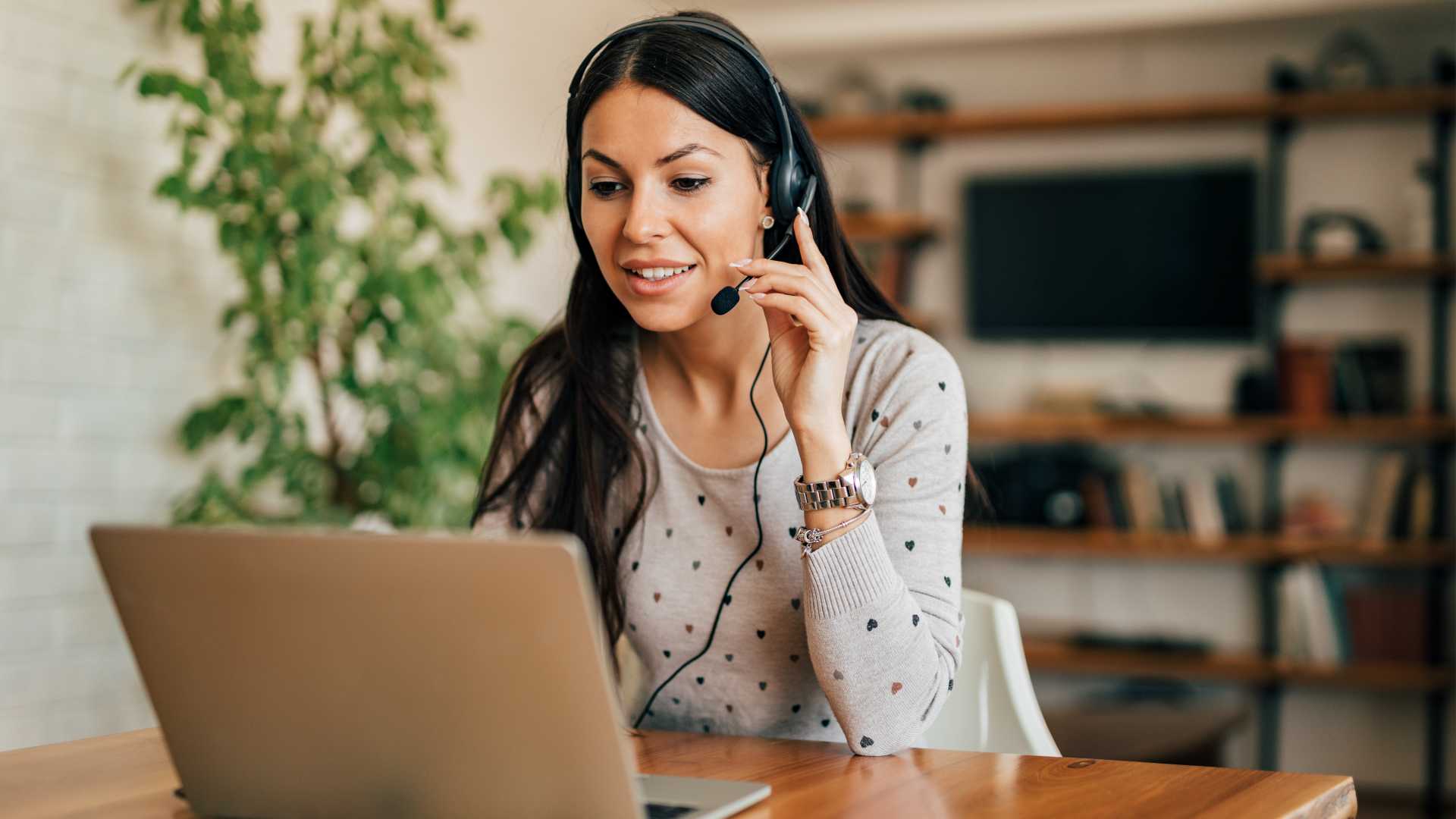 A woman wearing a headset working from home at a desk