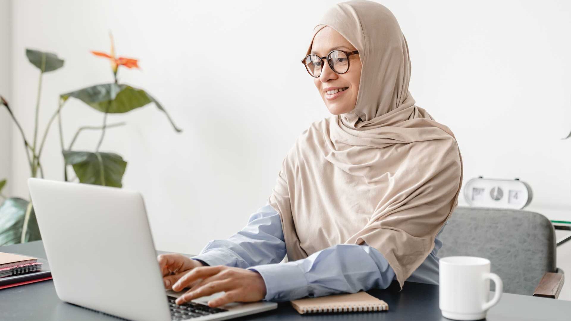 A woman sitting in front of an open laptop in a home office setting