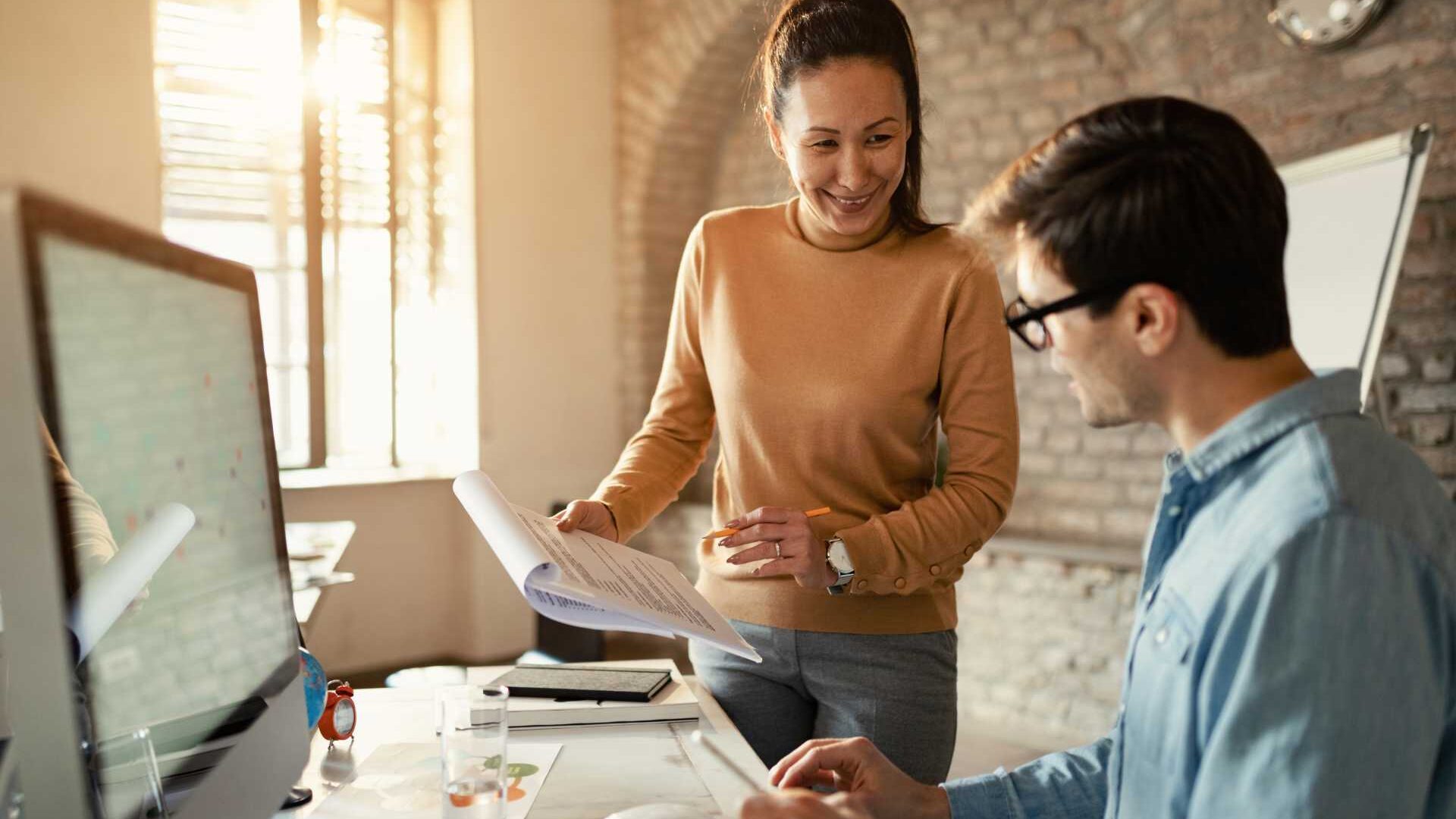 A male employee and a female employee collaborate in an office setting