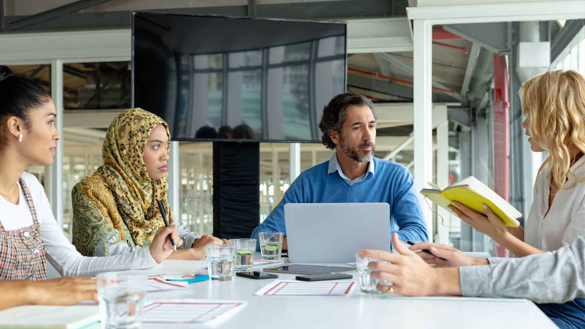 A diverse group of coworkers sit around a meeting table and debate over what learning tech to choose in 2024.