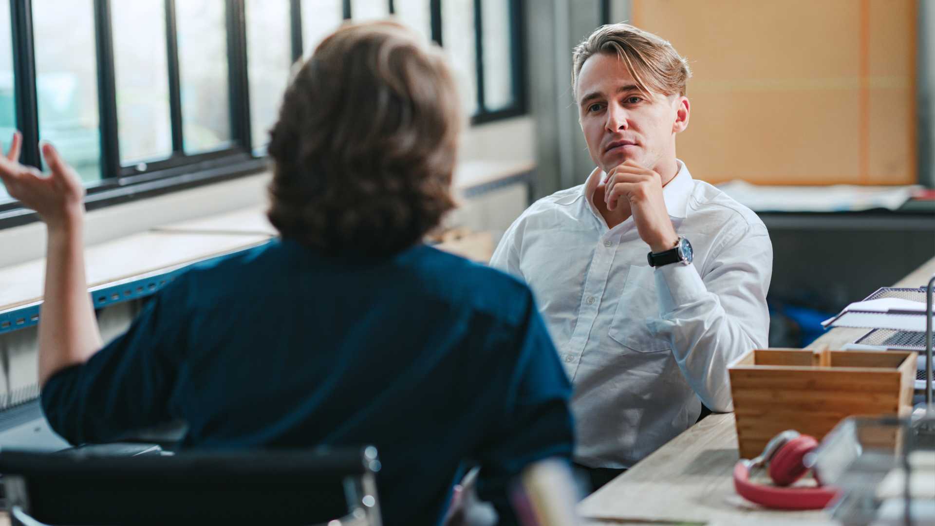Two businessmen engage in a discussion in a workplace setting
