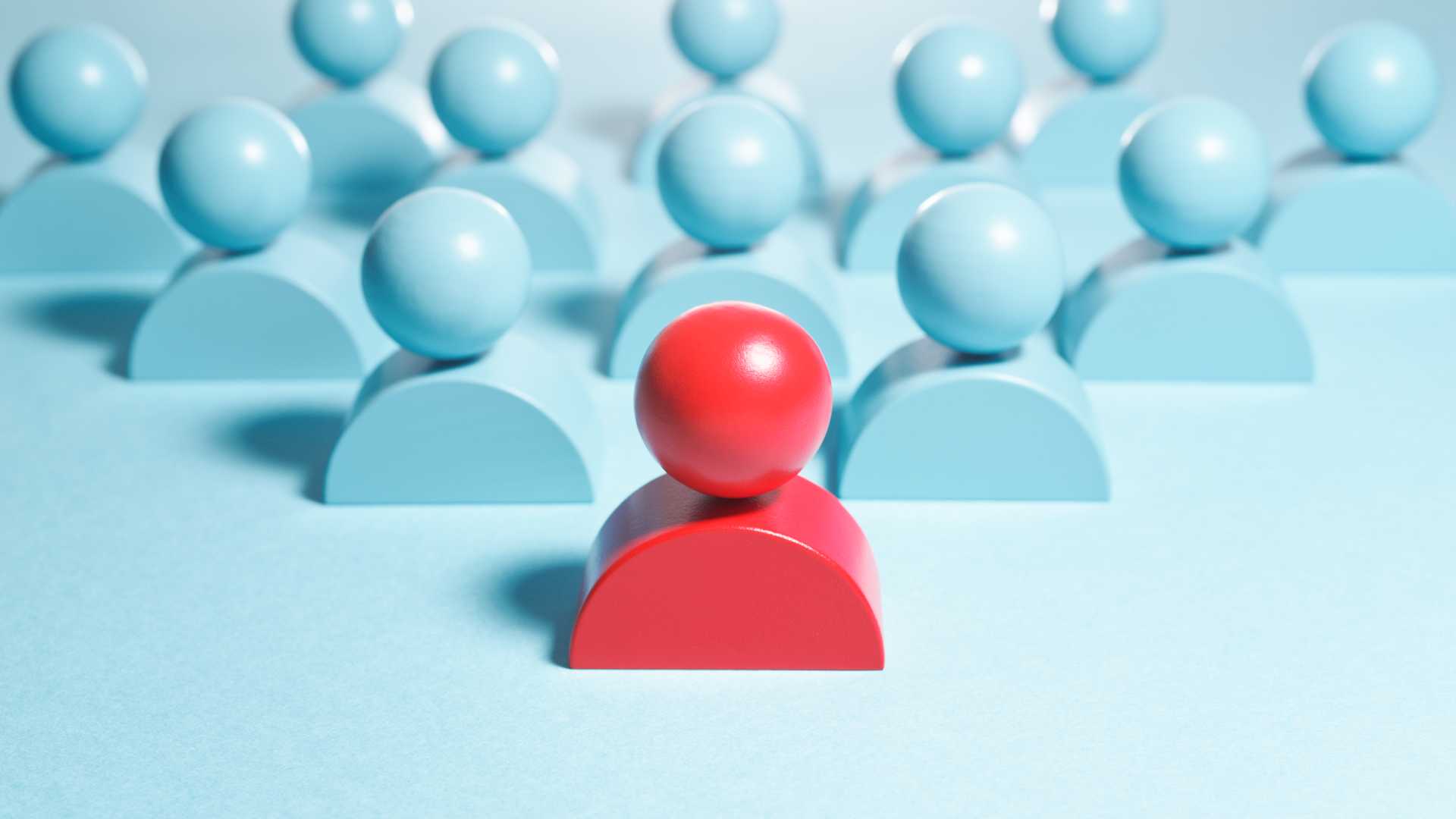Conceptual image representing leadership, blue figure heads with a red figure head leading the group