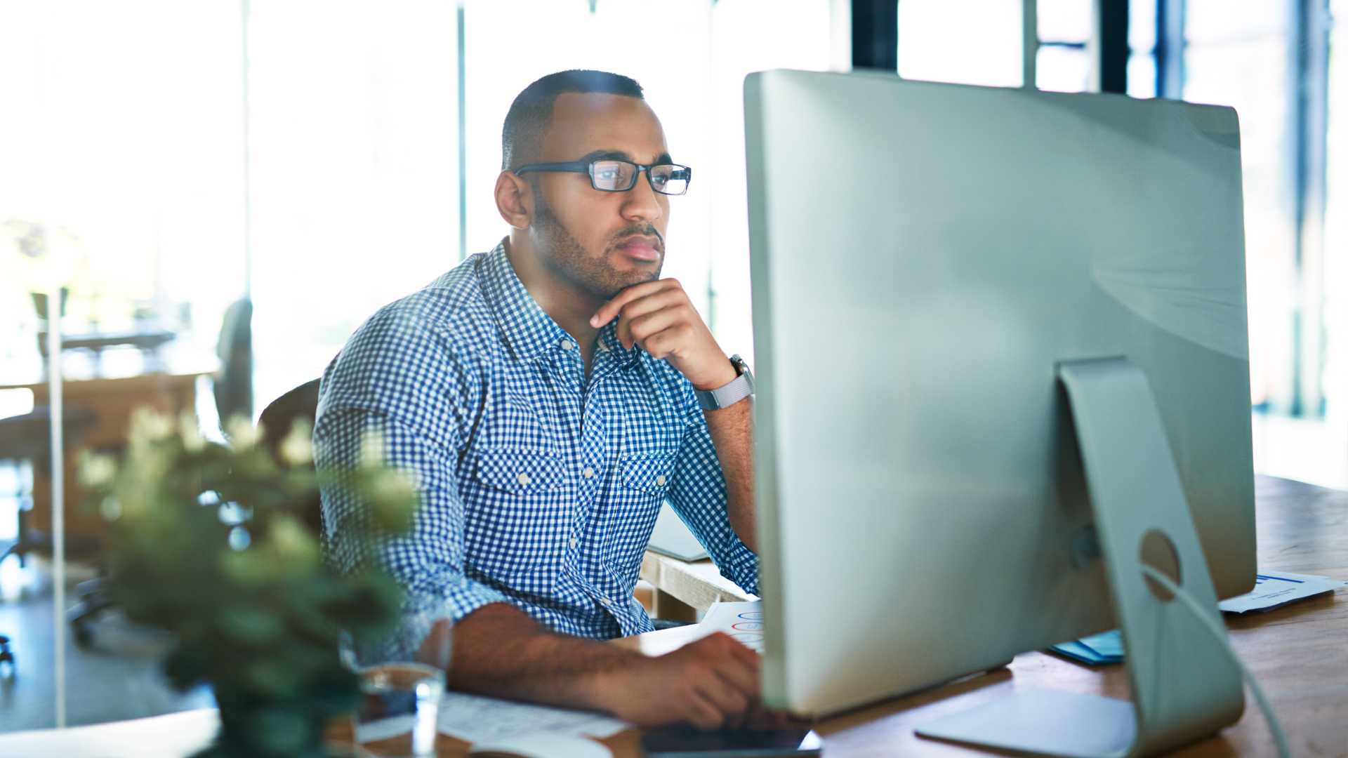 A learner is gazing at his monitor thoughtfully; he is fully engaged by AI-developed eLearning content.