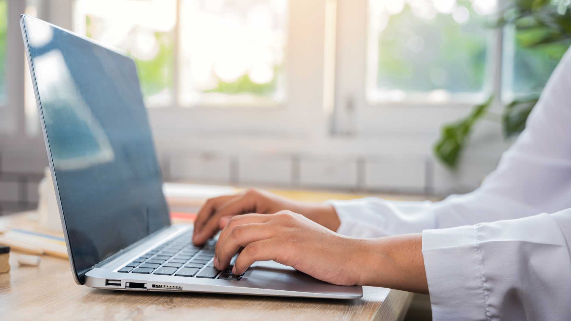 Close-up image of hands resting on a laptop in a work from home environment