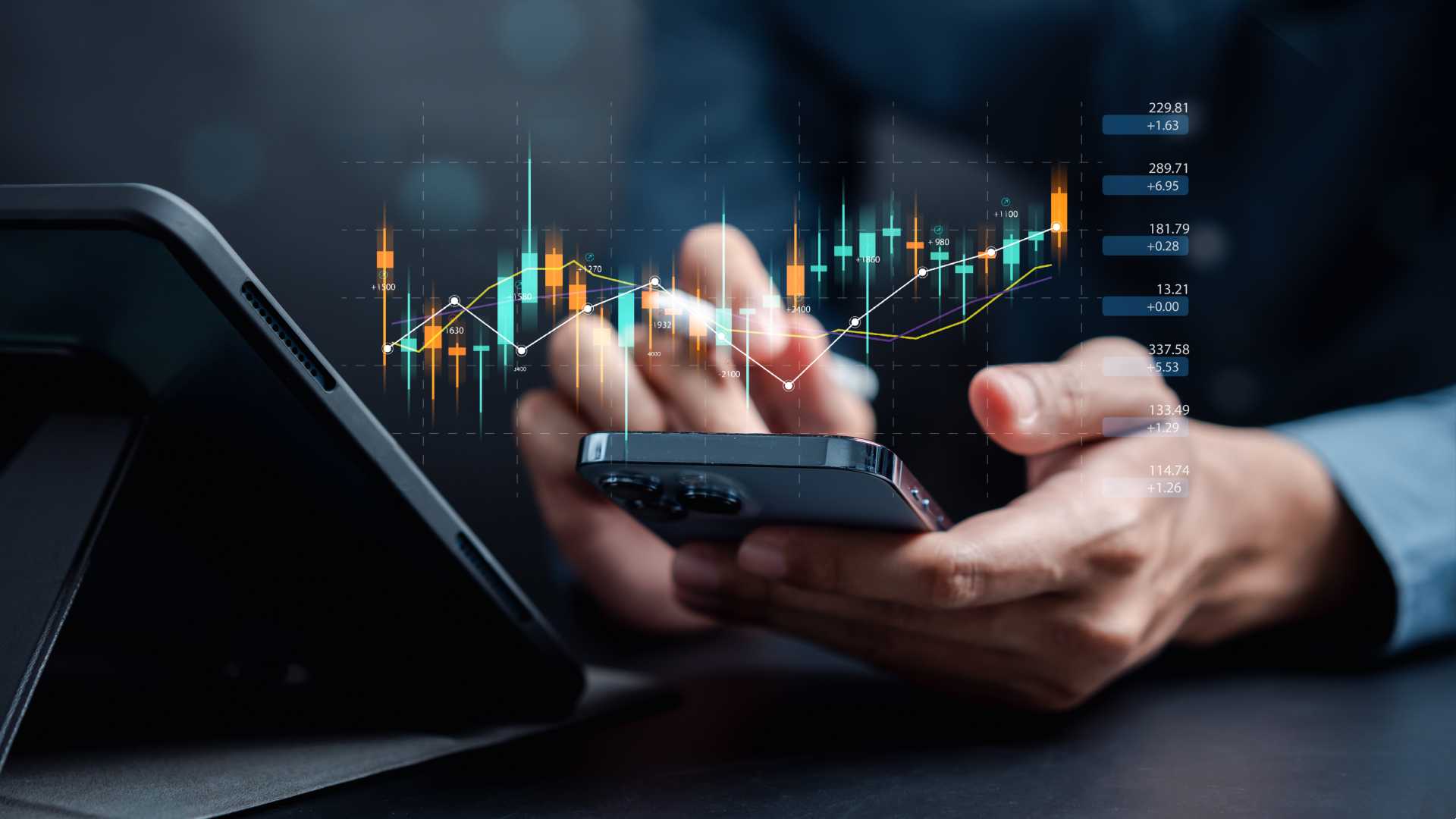 A photo of a person's hands as they use a smartphone to analyze trading data. A digital line graph is projected above the phone