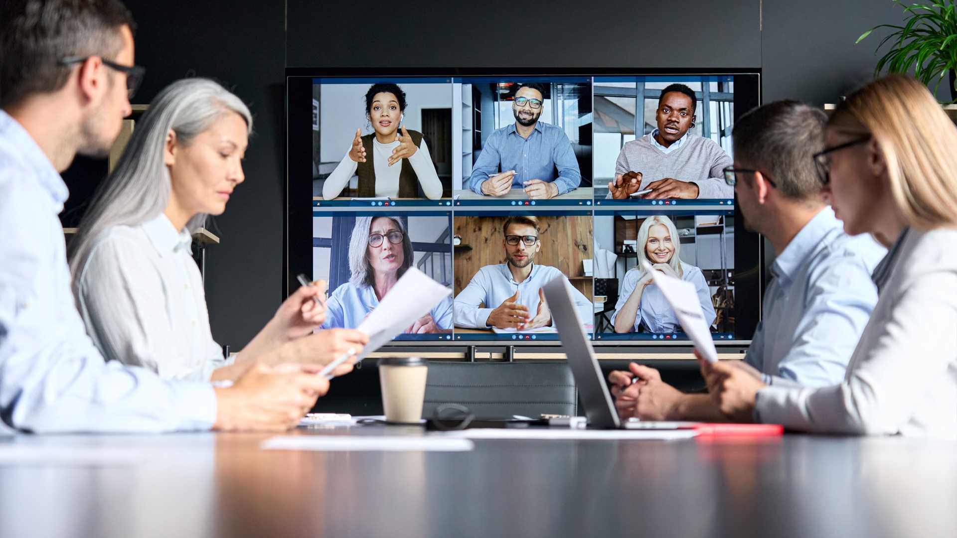 A hybrid team meeting takes place with in-person and virtual participants