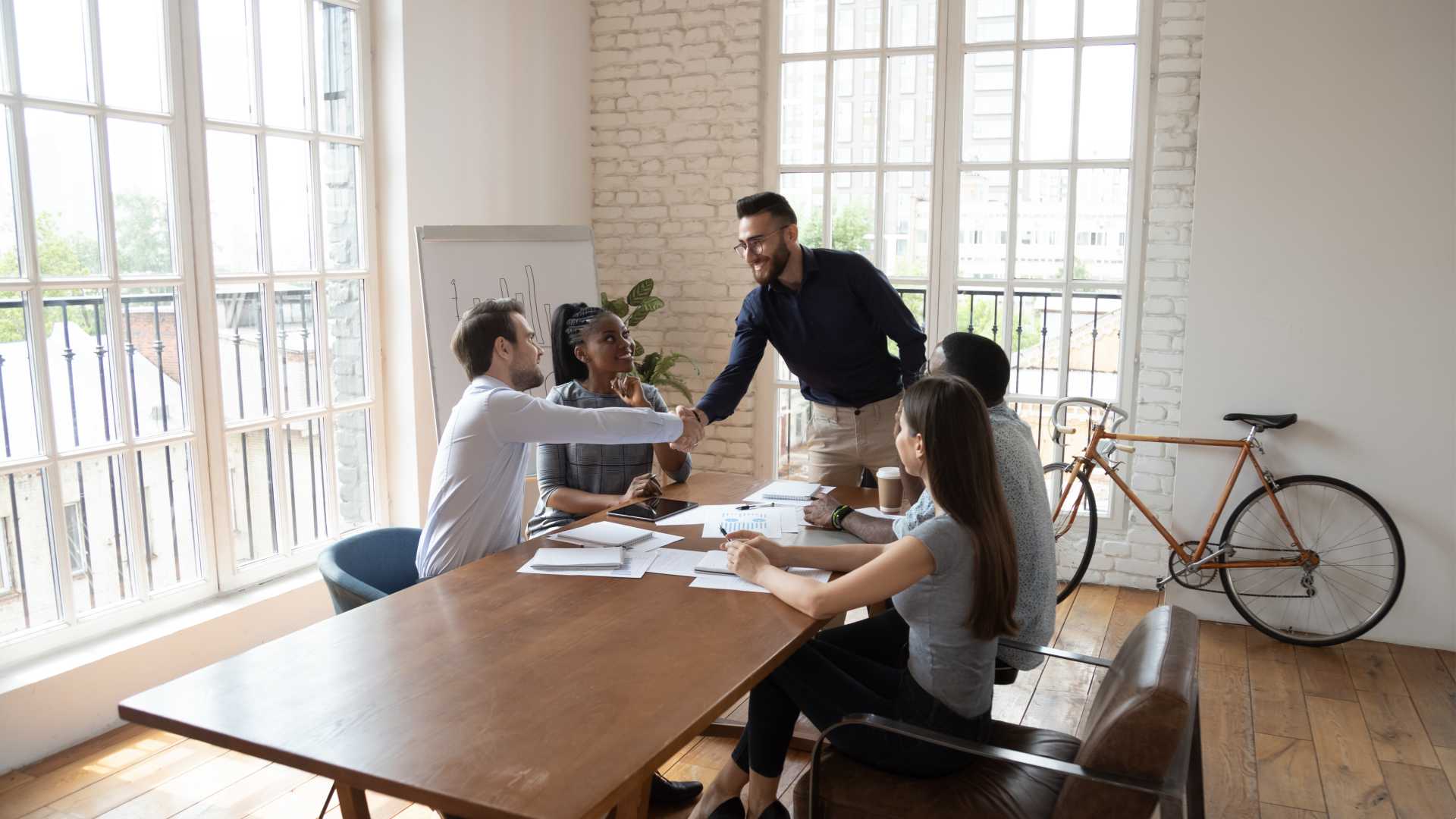 Group of cohorts sitting together at a conference table with documents spread between them ready to engage in collaborative dialogue; managing difficult conversations in decision-making.
