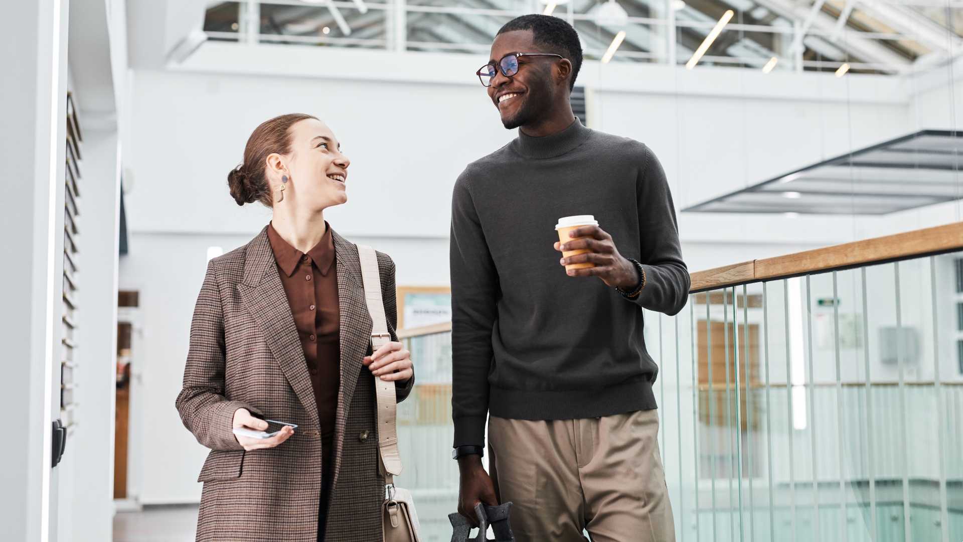 Two company workers either in-office desk workers or front-line workers sharing coffee and knowledge as they engage and connect with one another's diverse perspectives to further their learning and development skills sets.