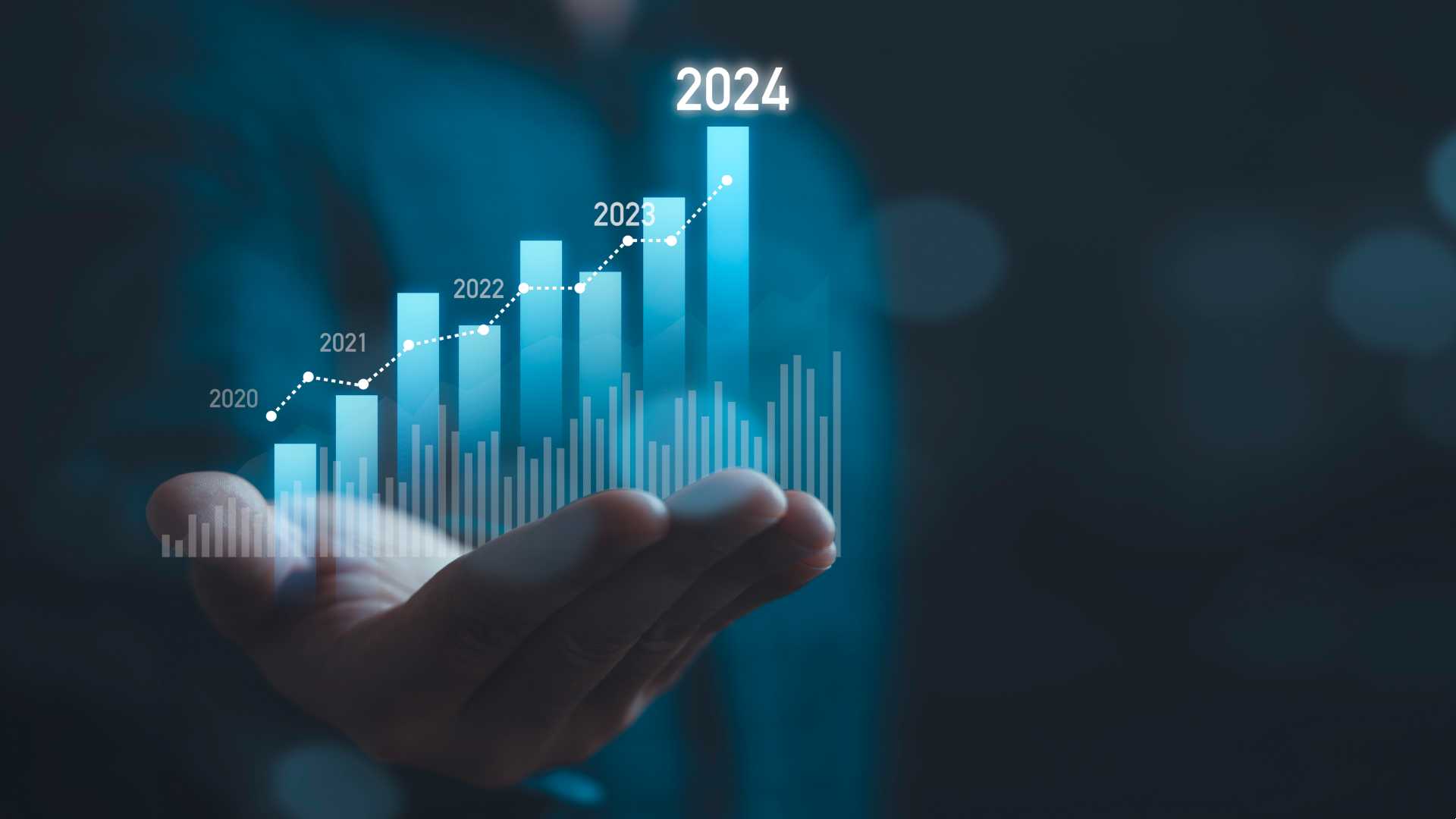 Hand holding up a holographic designed image of ethereal blue bars in a bar graph, going from late 2010's to current.