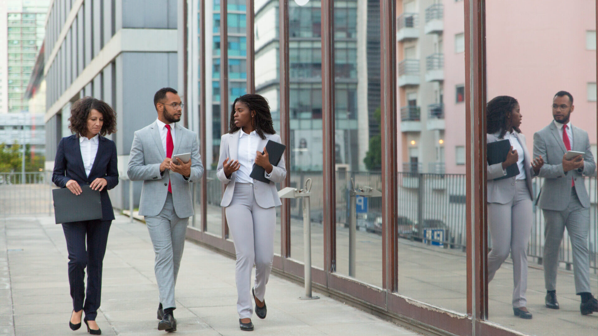 Three business colleagues walking on a city sidewalk discussing a project