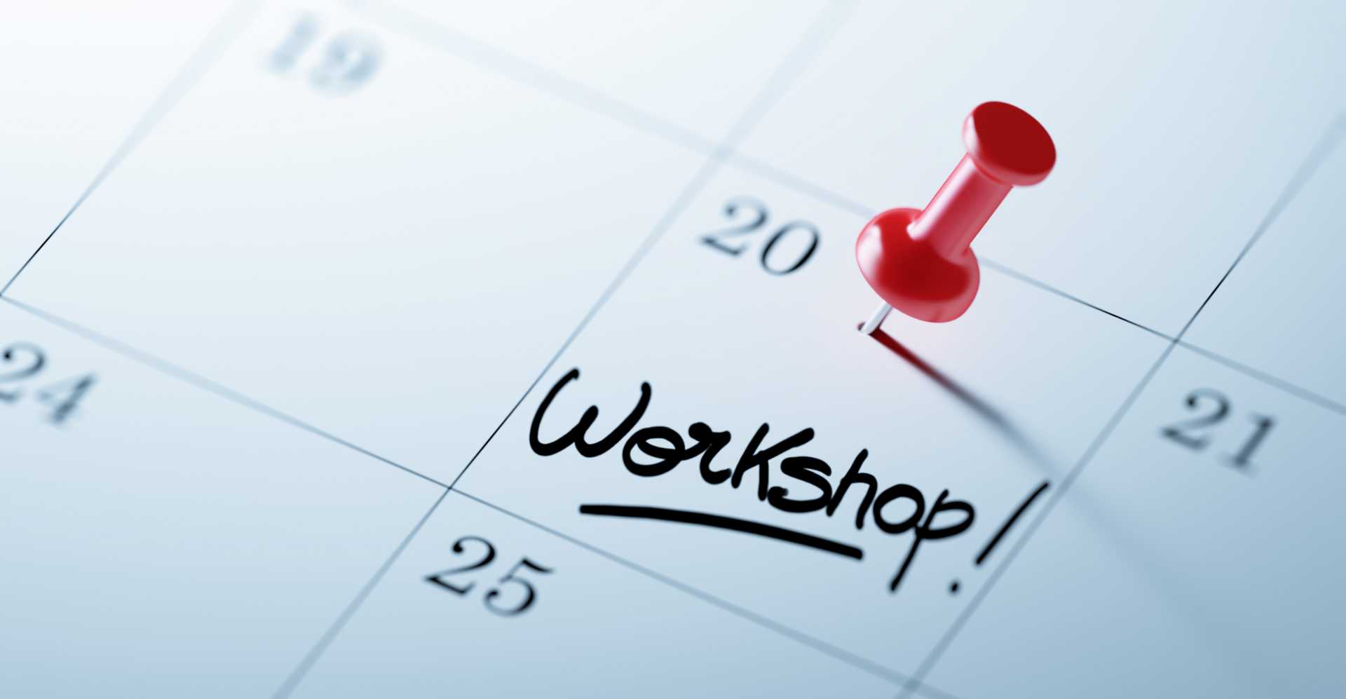 A Calendar with a red push pin. The words Workshop written on a white notebook.