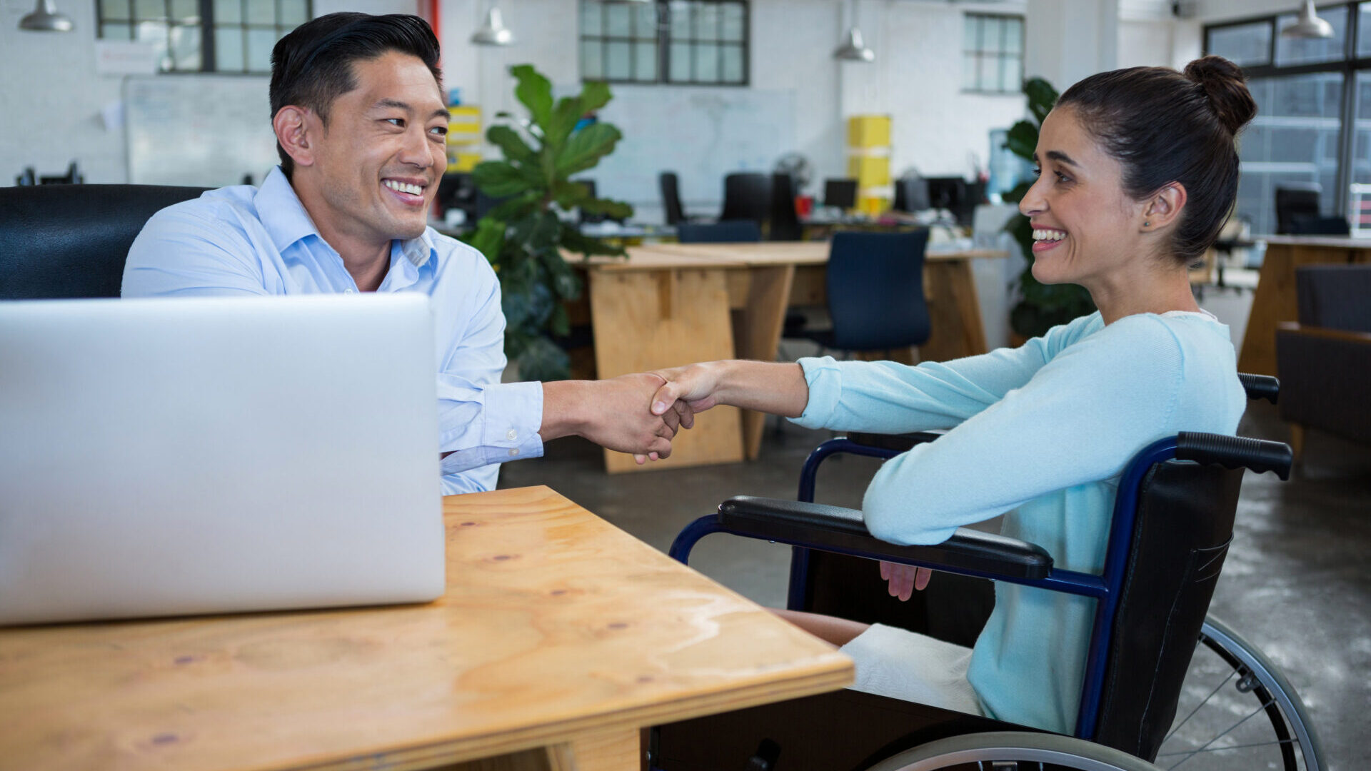 Businessman shaking hands with disabled coworker in office