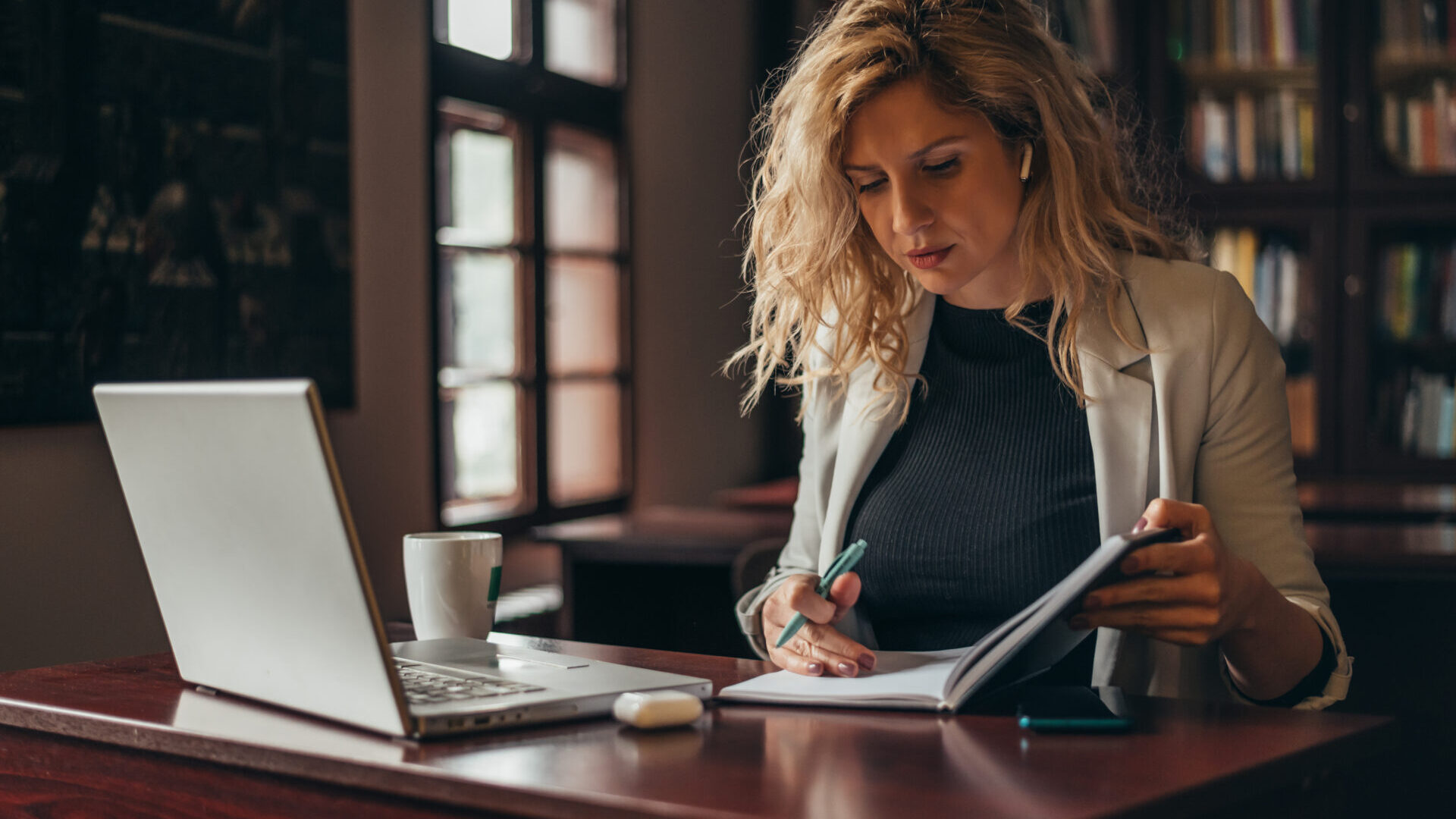 Woman sitting down at an office desk and using her notebook.