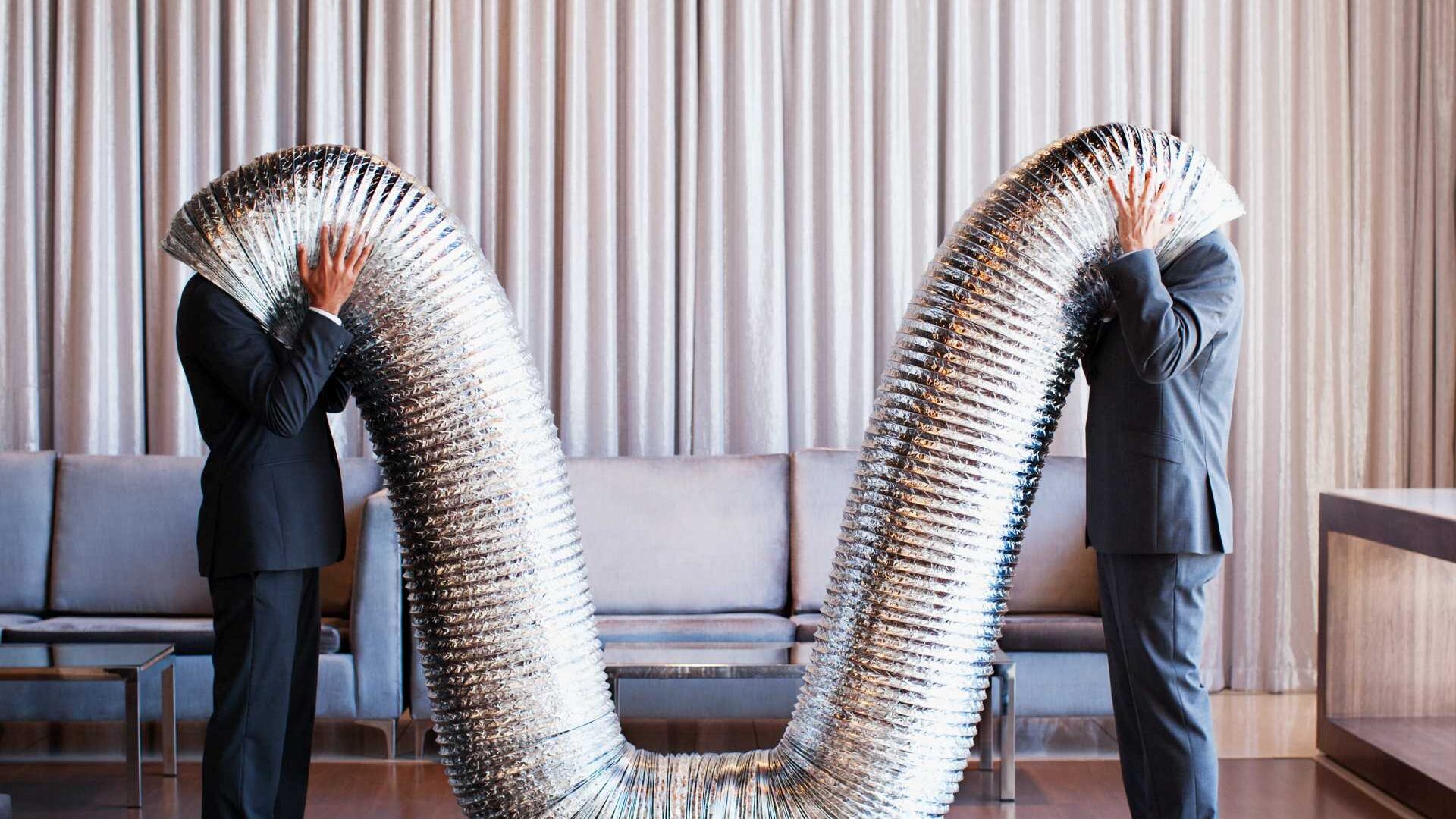 Two businessmen are sticking their heads in a funnel.