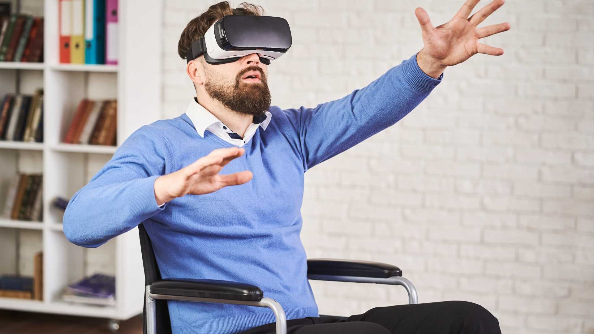 Man sitting in a wheelchair using a VR headset.