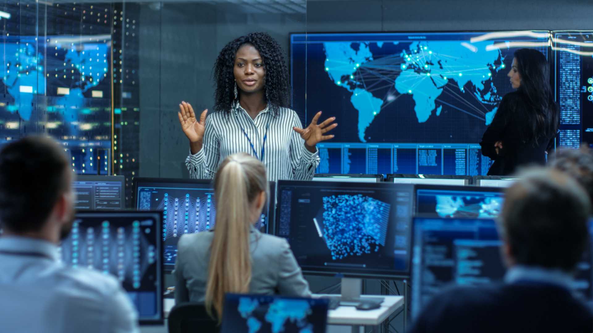 Woman speaking to her coworkers while standing up. She is leading a conversation