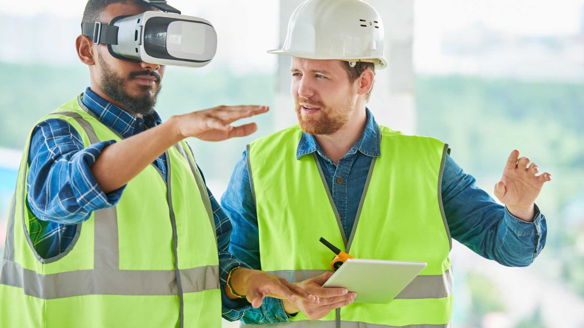 Two construction workers, one using VR googles and doing training.