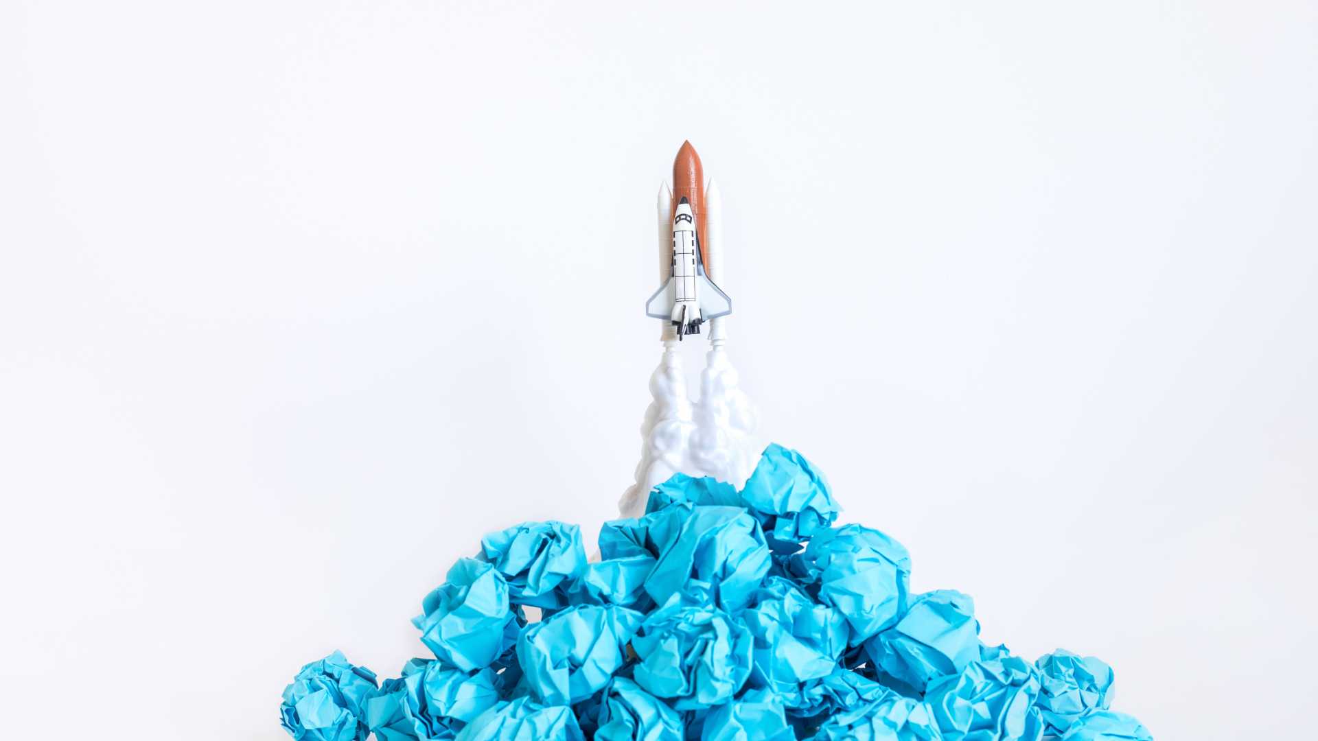 Rocket ship made from paper and cardboard over blue crumpled paper to simulate flames.