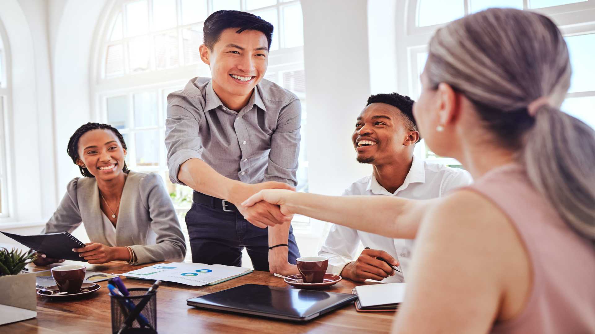 Team meeting and collaboration with Team Leader shaking hand.