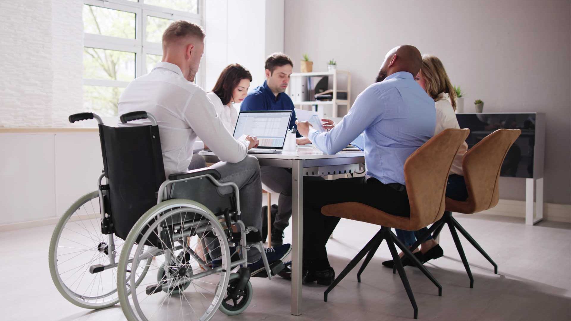 elevate sales performance article image - a team meets around a table in the workplace