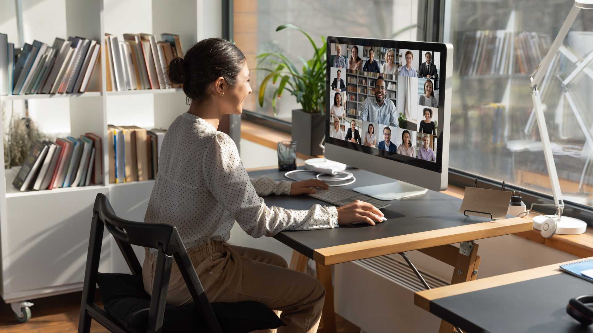 Woman working on a desktop from home, in a meeting.