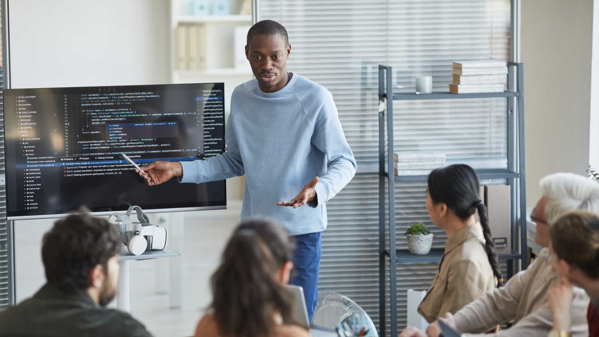 Co-worker giving his team a presentation with graphs and coding.