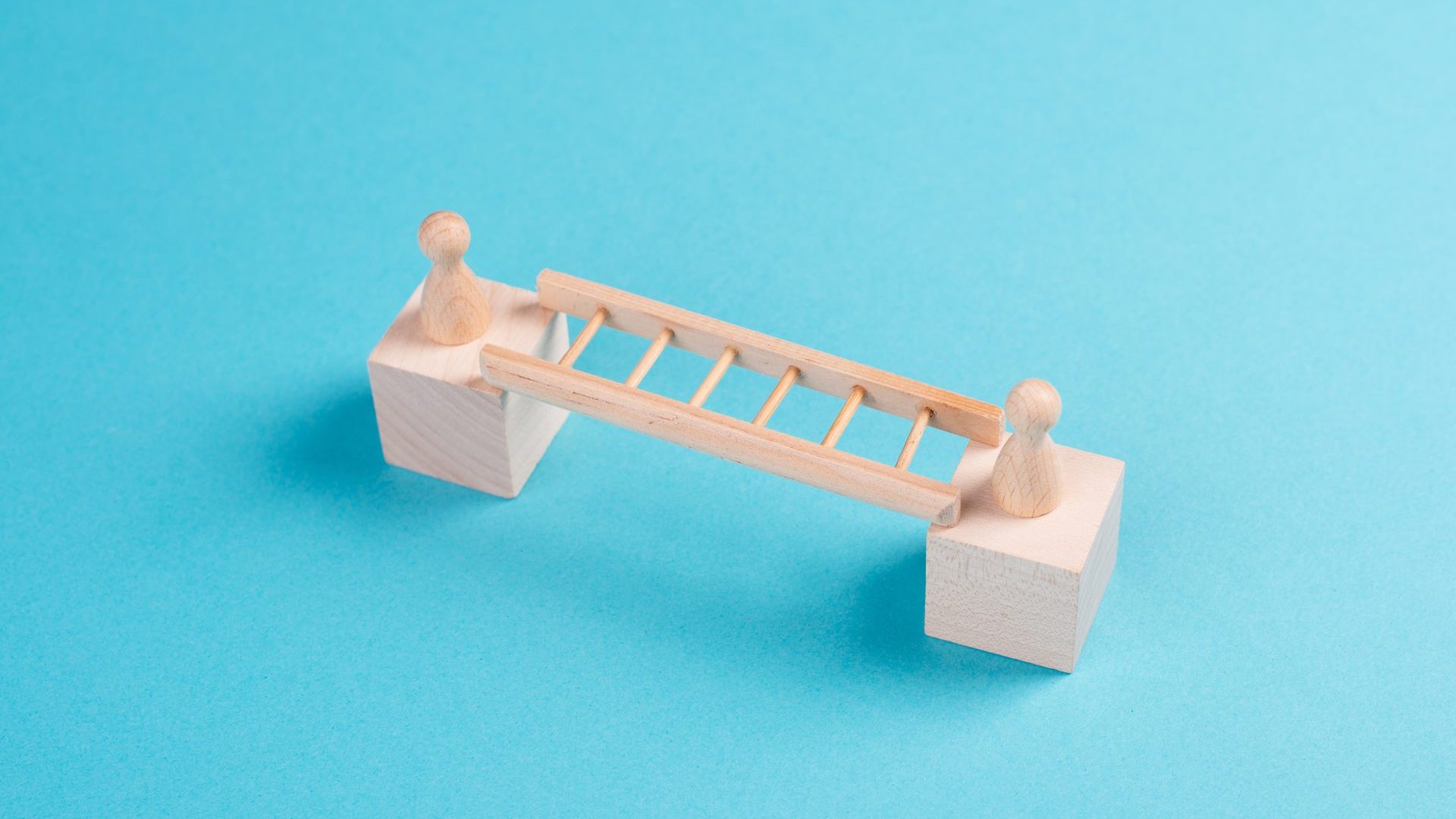 Two wooden dolls connected by a bridge representing human connection and empathy