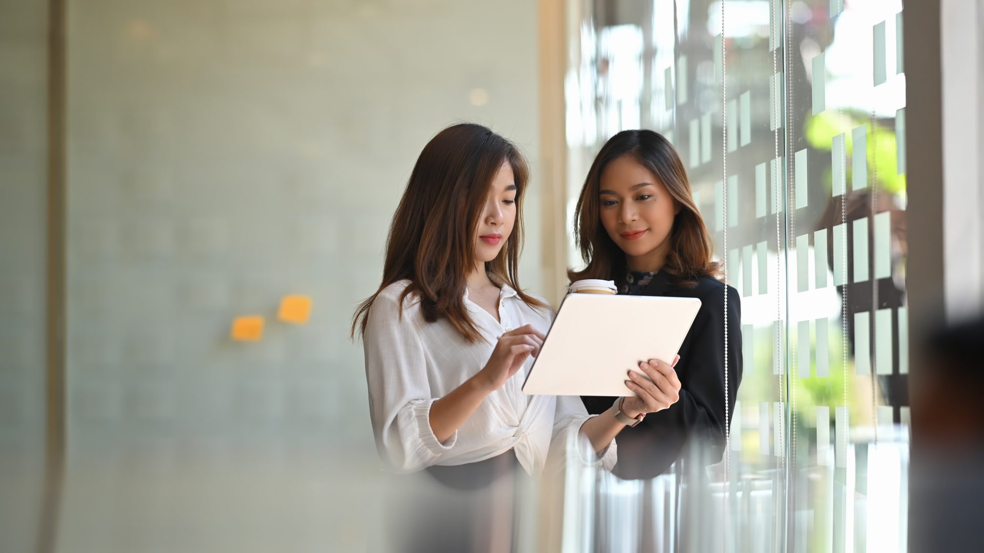 Two female coworkers looking at an iPad for a work assignment.